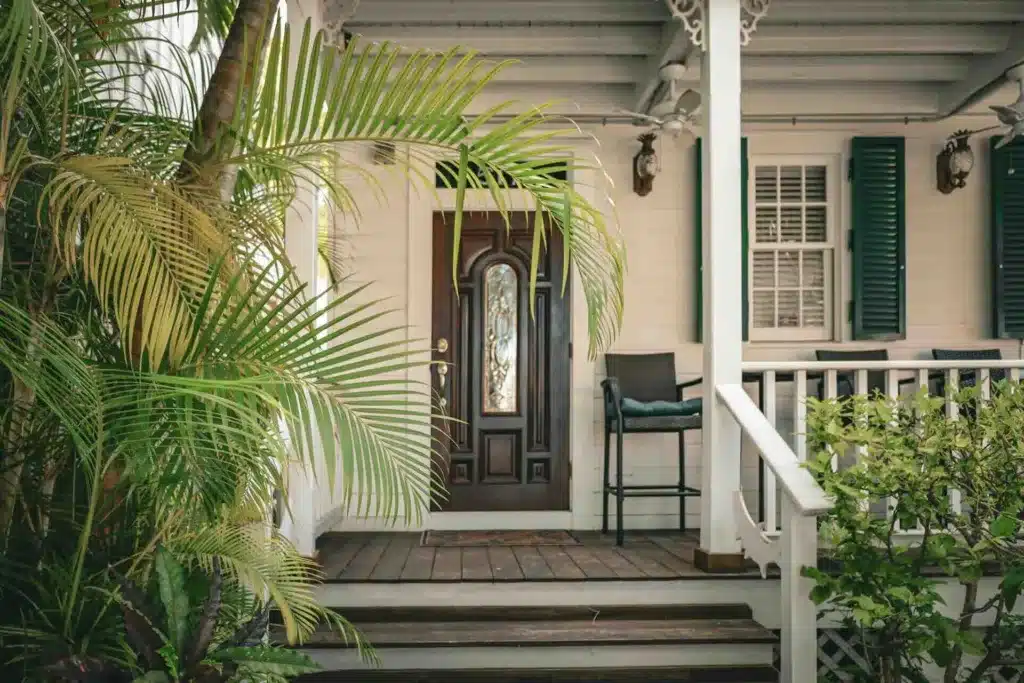Colonial house wood-look entry door with tropical plants - Lindholm Exteriors