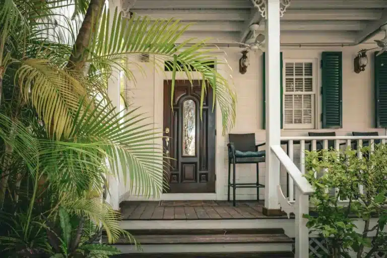 Colonial house wood-look entry door with tropical plants - Lindholm Exteriors
